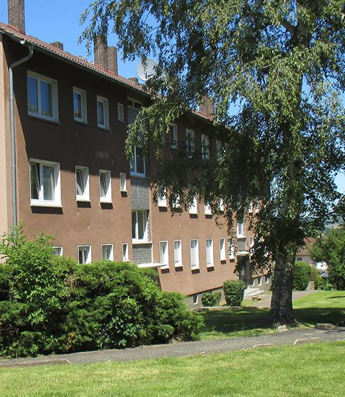 Das Foto zeigt ein Mehrfamilienhaus in Lauterbach. Dieses liegt an einer Grünfläche mit einem Fußweg.
