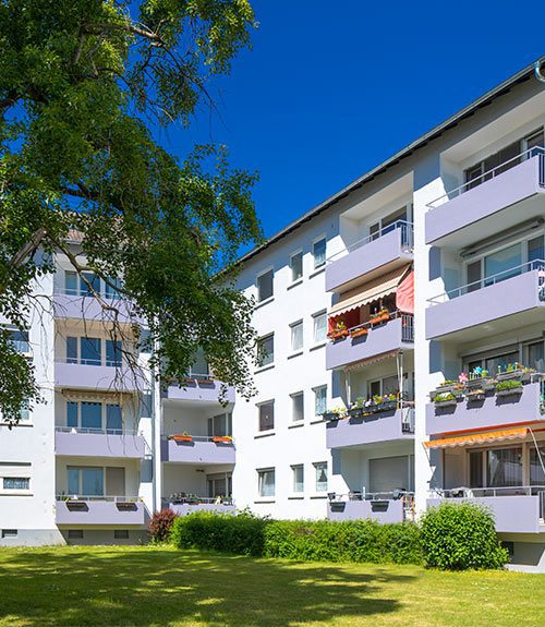 Das Foto zeigt ein Mehrfamilienhaus in Hattersheim. Es besitzt mehrere Balkons und liegt an einer Grünfläche.